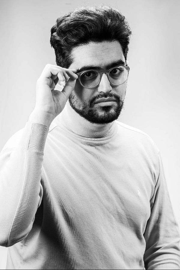 Black and white portrait of a man adjusting his glasses.