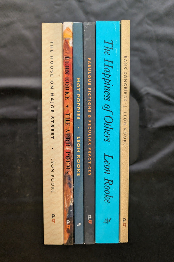 Set of books by Leon Rooke on a dark fabric background