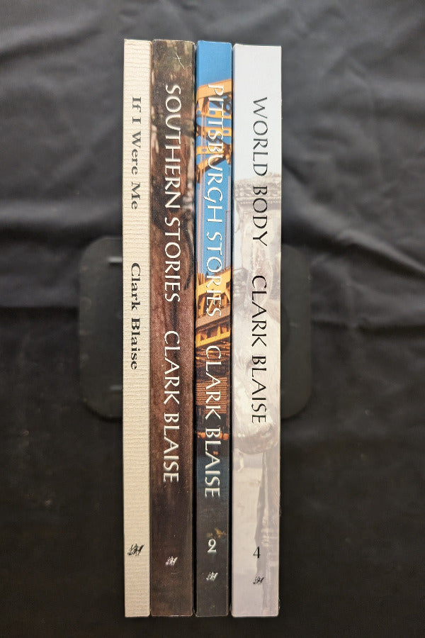 Stack of books by Clark Blaise on a dark fabric background