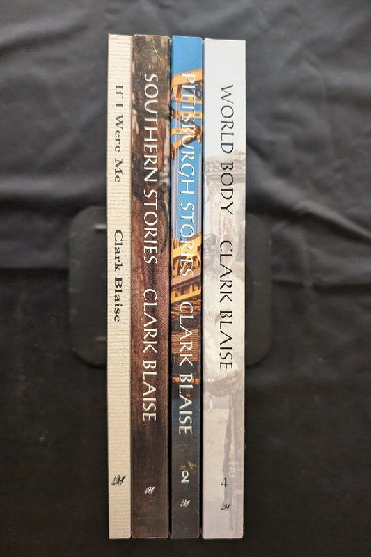 Stack of books by Clark Blaise on a dark fabric background