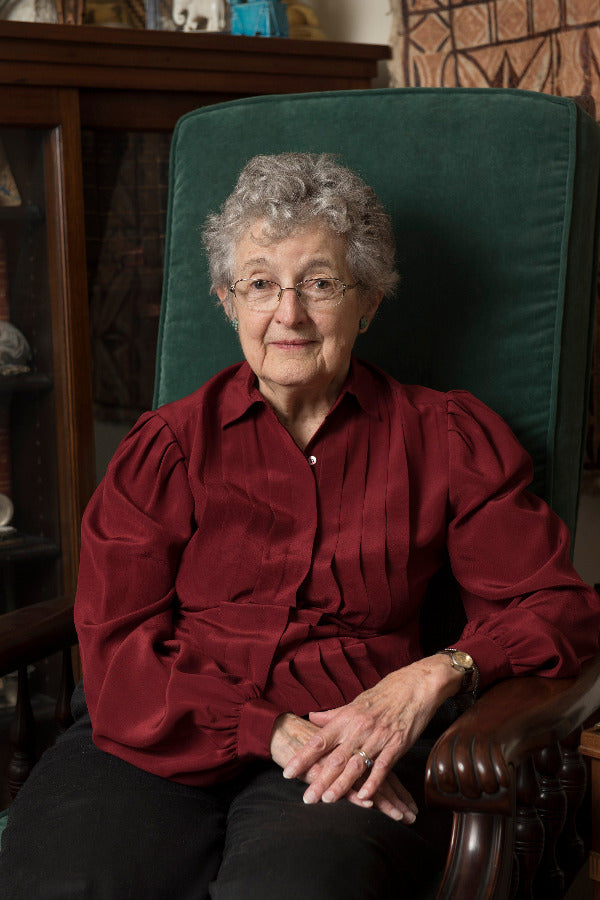 Woman sitting in a green chair wearing a red blouse in an indoor setting.