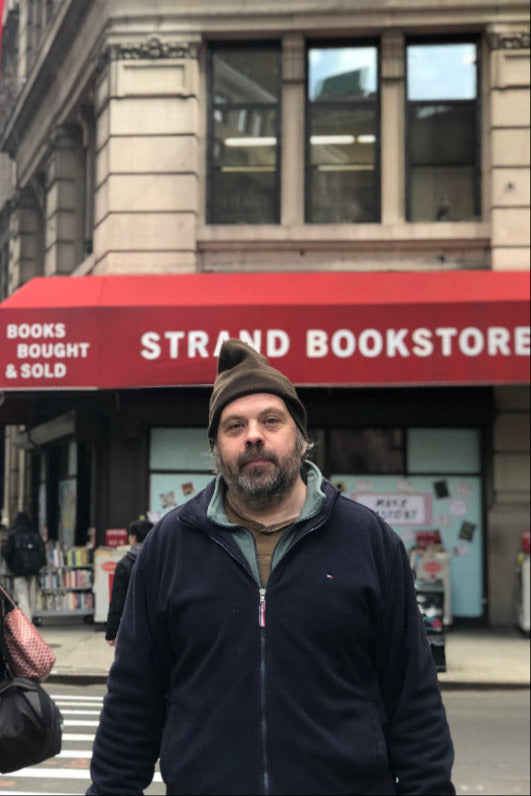 Shane Neilson standing in front of the Strand Bookstore with a red awning.